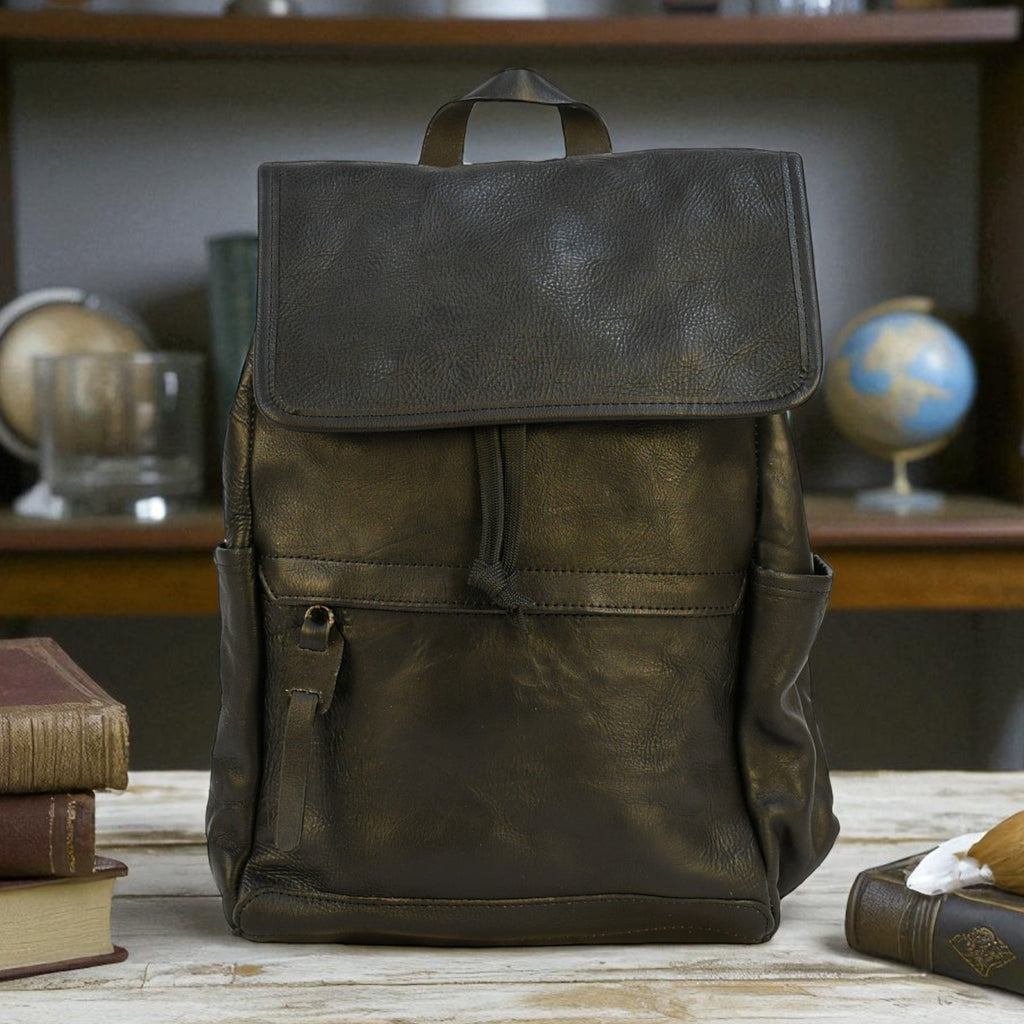 Brown modern rugged leather backpack on a wooden table with books and a globe in the background
