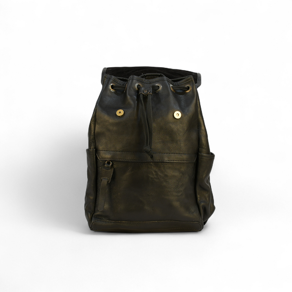 Brown modern rugged leather backpack on a wooden table with books and a globe in the background