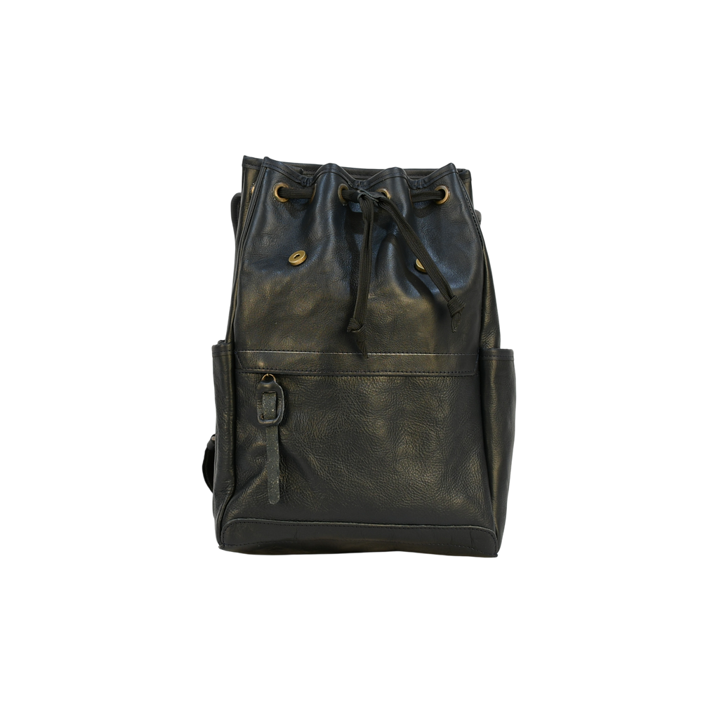 Dark leather modern rugged backpack on a wooden surface with books and a stone wall background