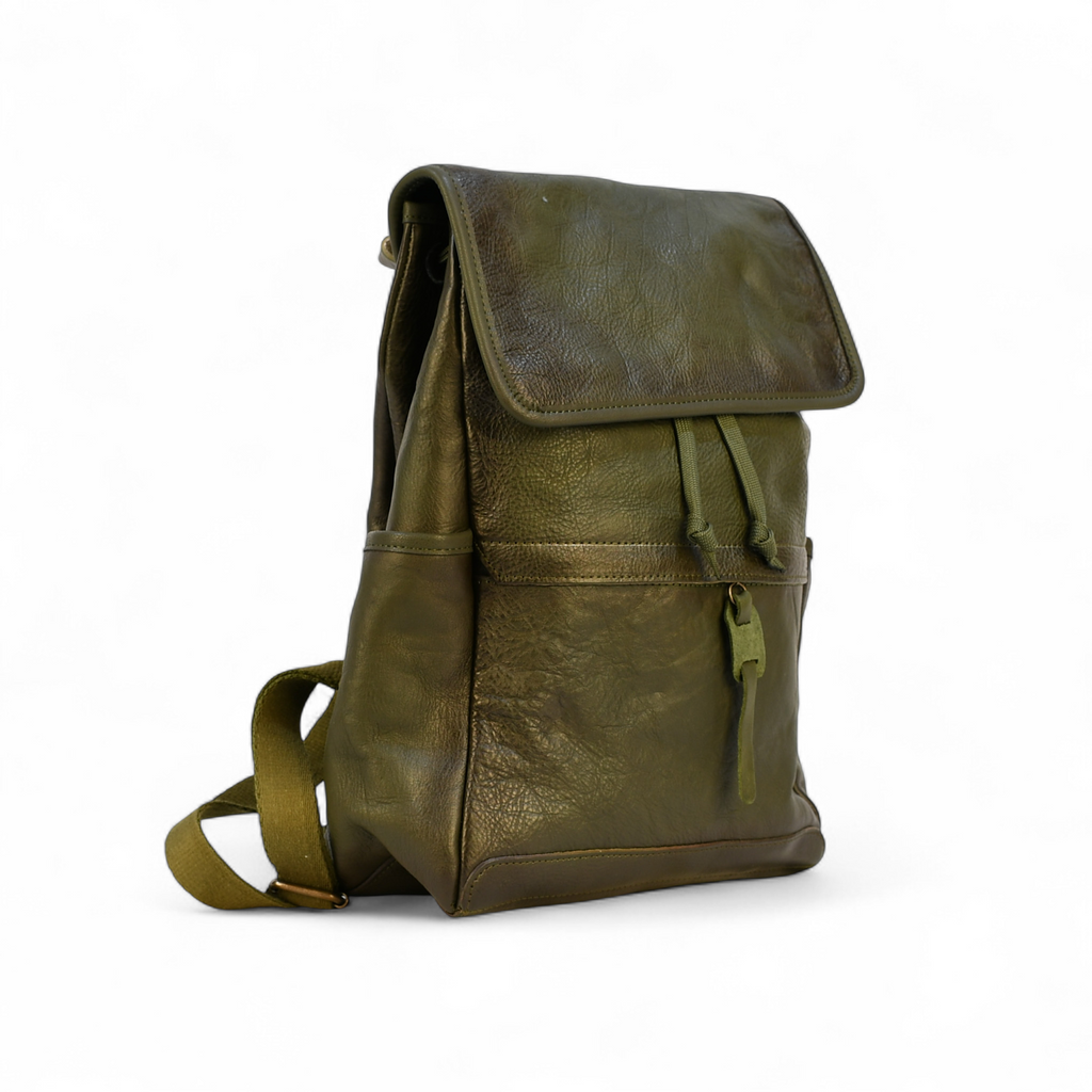 Green leather modern rugged backpack on a wooden table with a blurred indoor background