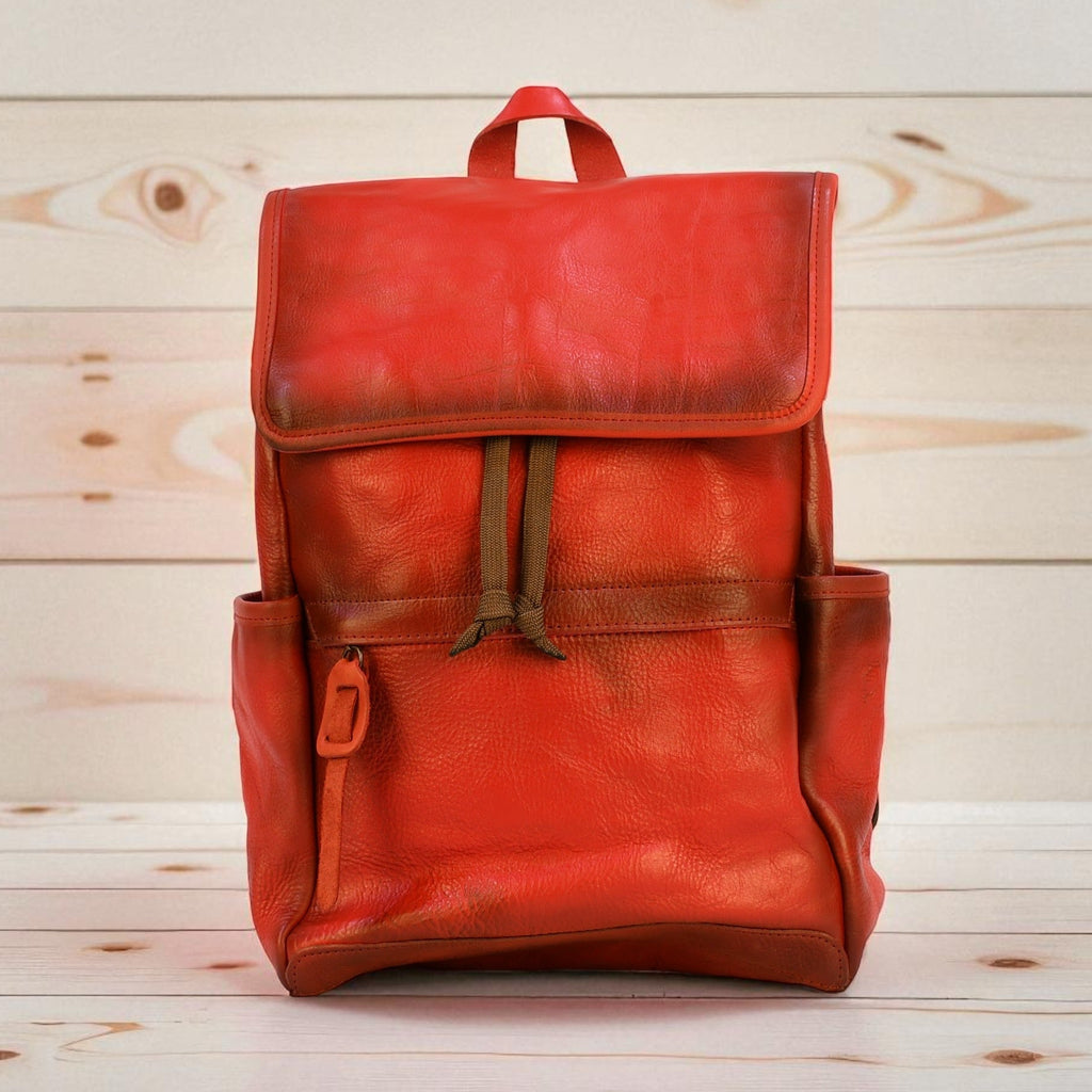 Red modern rugged leather backpack on a wooden surface