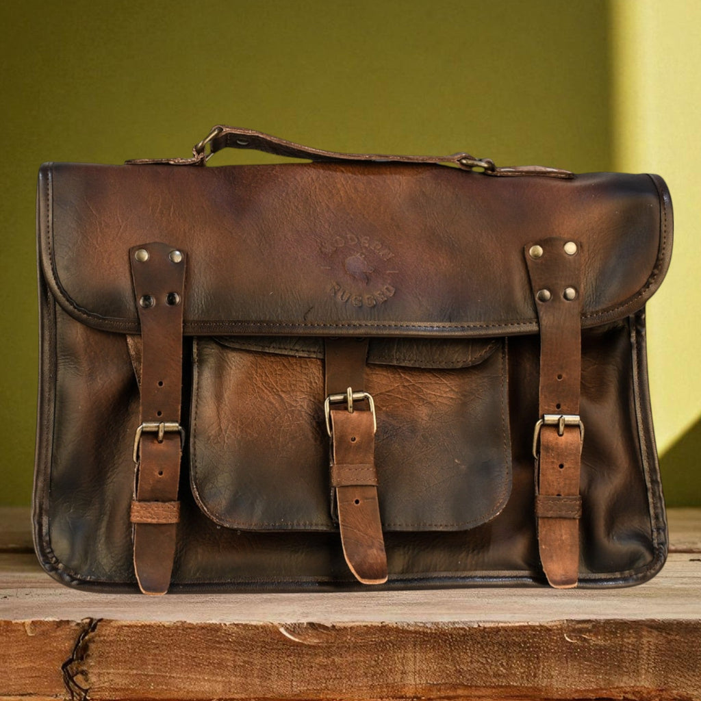 Brown leather laptop bag on a wooden surface with a green background