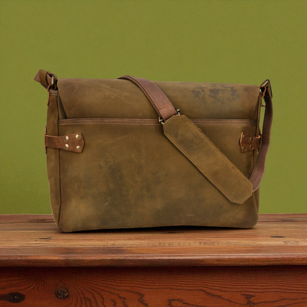 Olive leather bag on a wooden surface with a green background