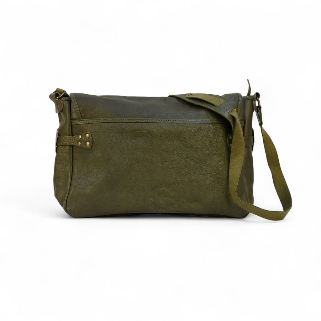 Green leather modern rugged messenger bag on a wooden surface with vintage books in the background