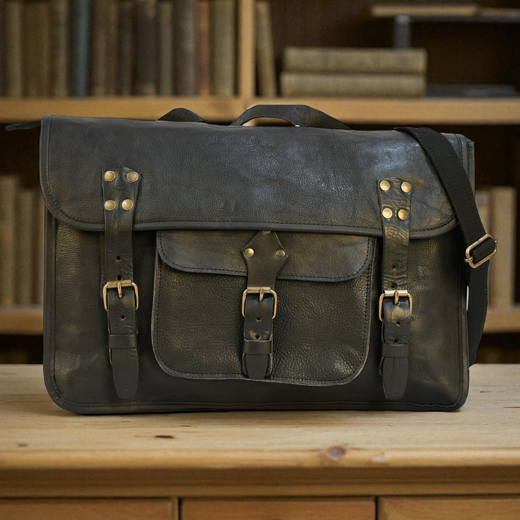 Vintage-style leather satchel bag on a wooden surface with bookshelf in the background