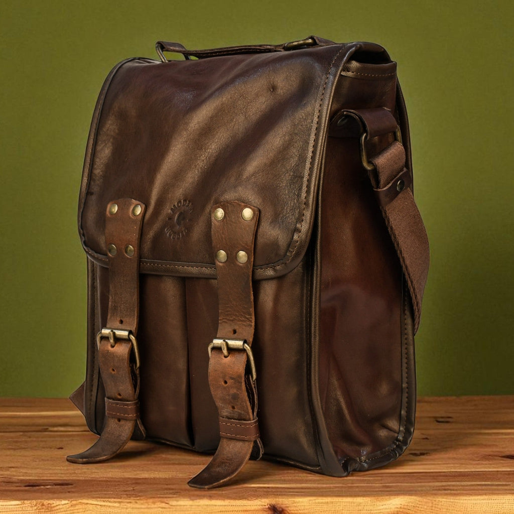Brown modern rugged leather bag on a wooden surface with a green background
