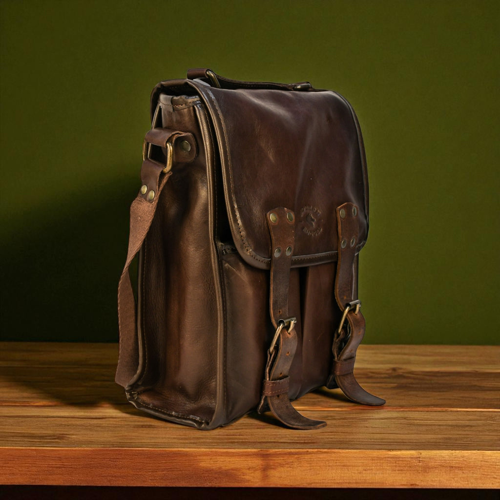 Brown leather bag on a wooden surface with a green background