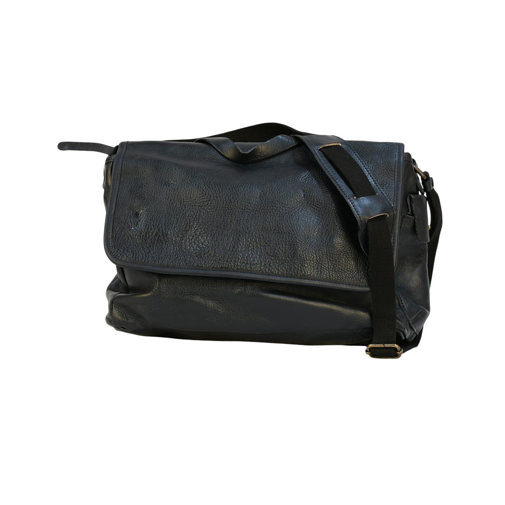 Black leather modern rugged messenger bag on a wooden table with a gray background