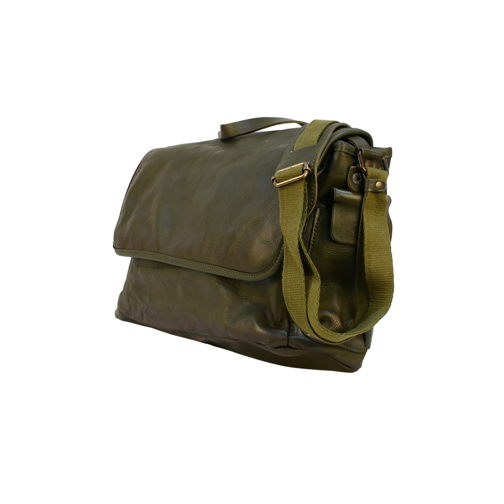 Green modern rugged leather bag on a wooden desk with bookshelves and a window in the background