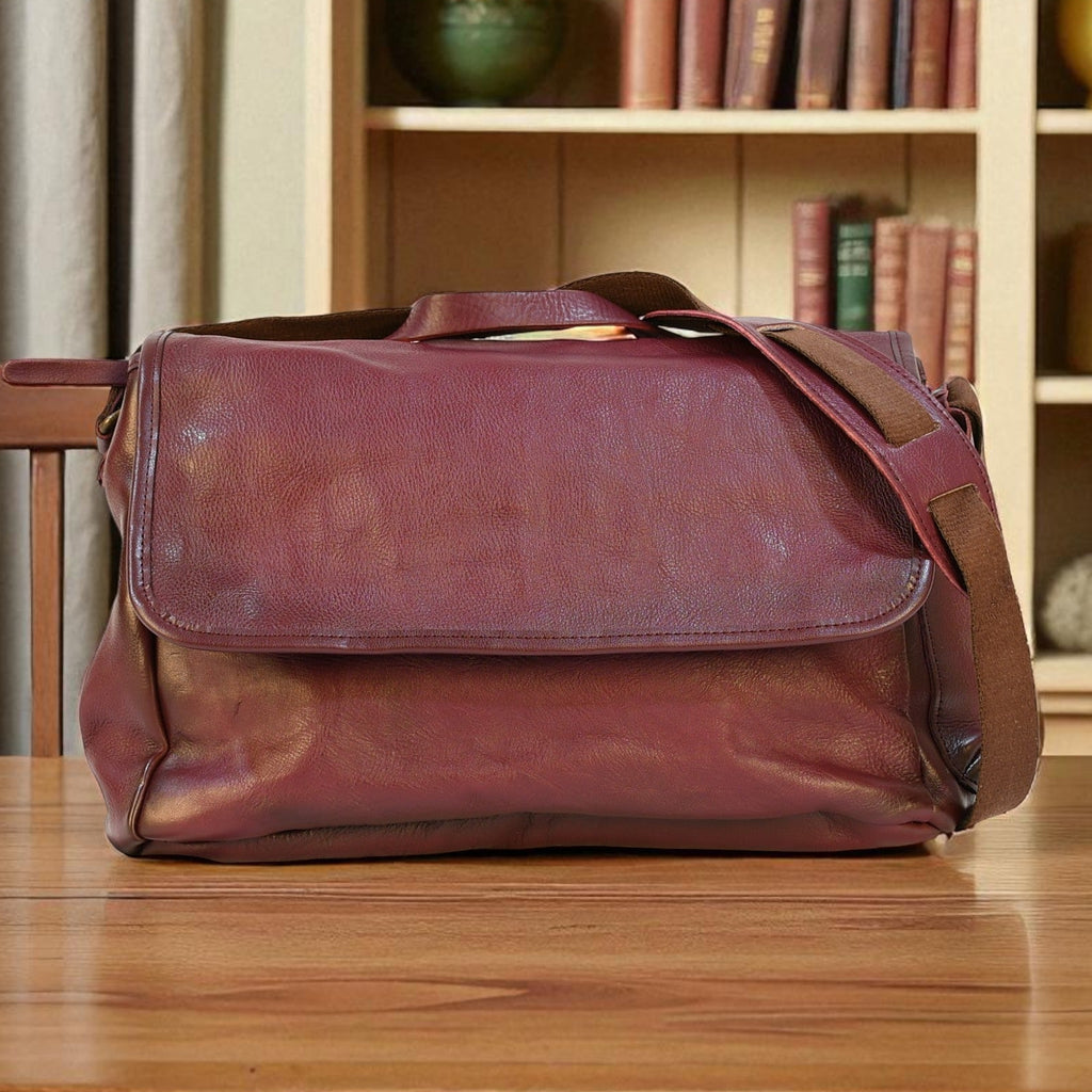 purple modern rugged leather bag on a wooden table with a bookshelf in the background