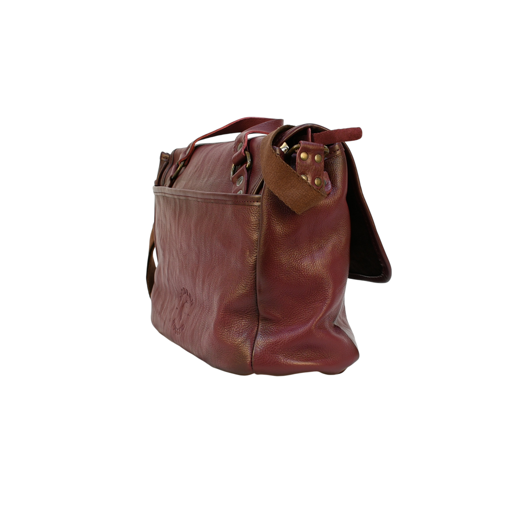 purple modern rugged leather bag on a wooden table with a bookshelf in the background