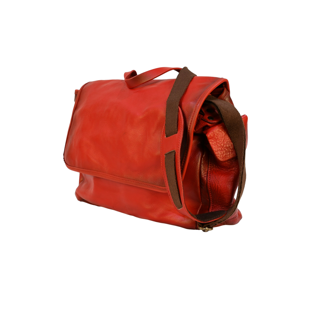 Red modern rugged leather bag on a wooden surface with books in the background