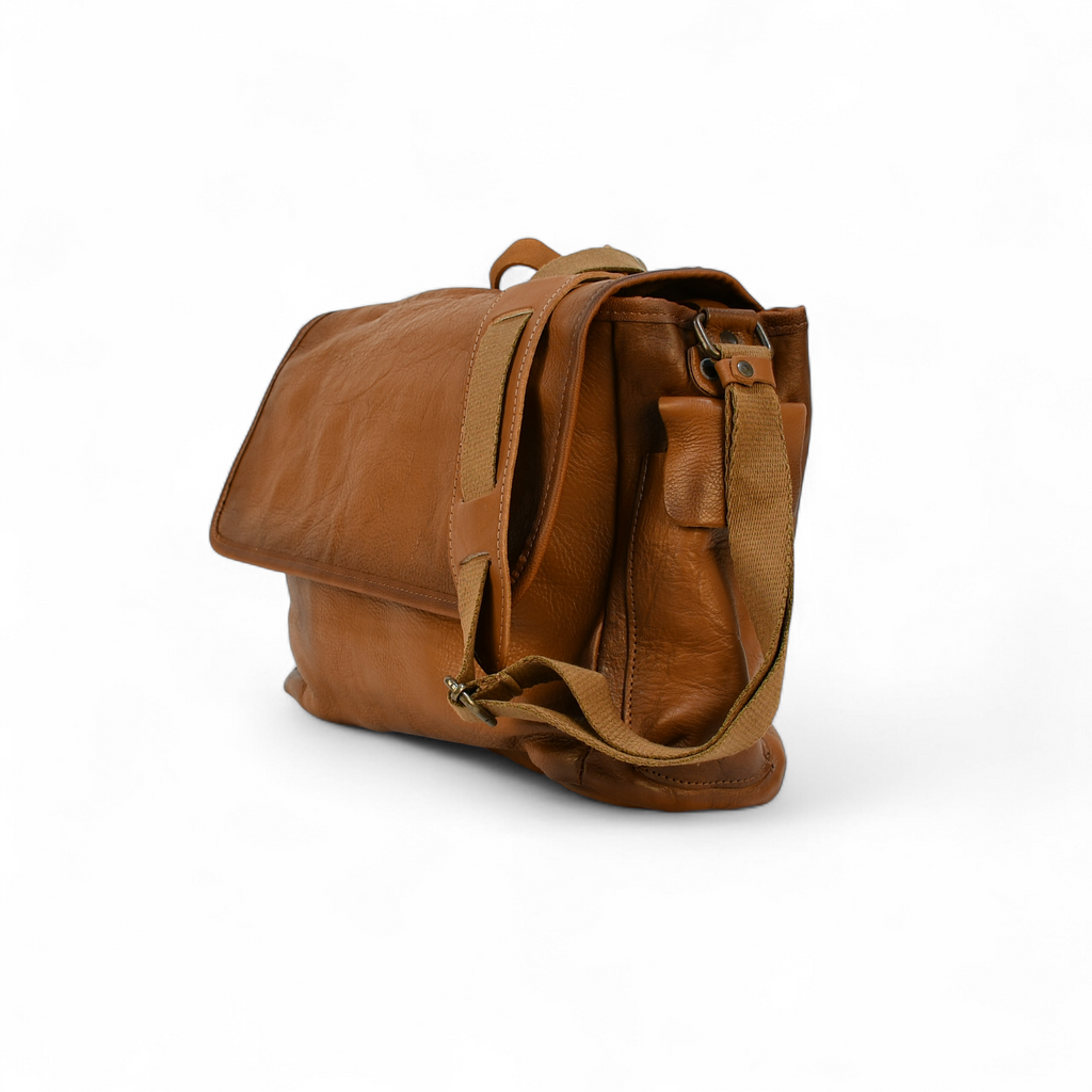Brown leather modern rugged messenger bag on a surface with a window in the background