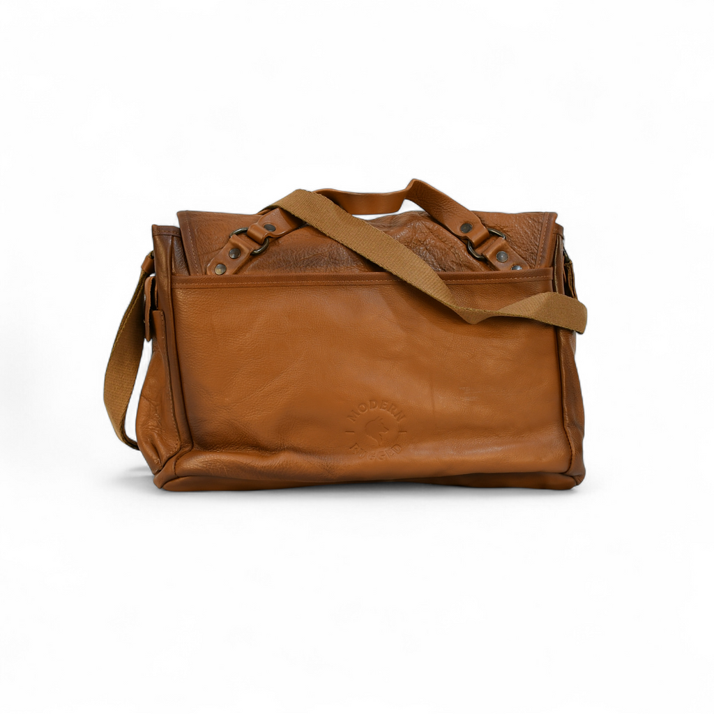 Brown leather modern rugged messenger bag on a surface with a window in the background