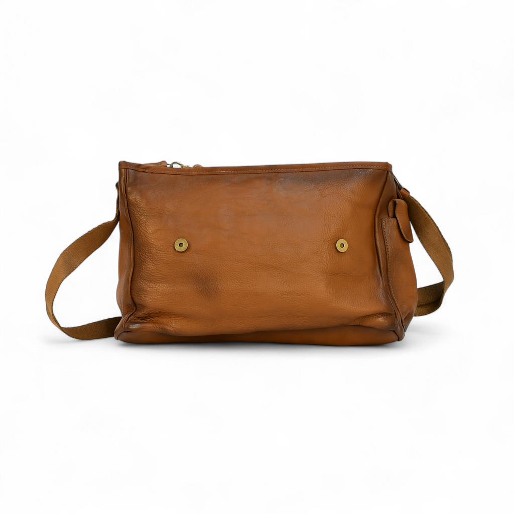 Brown leather modern rugged messenger bag on a surface with a window in the background