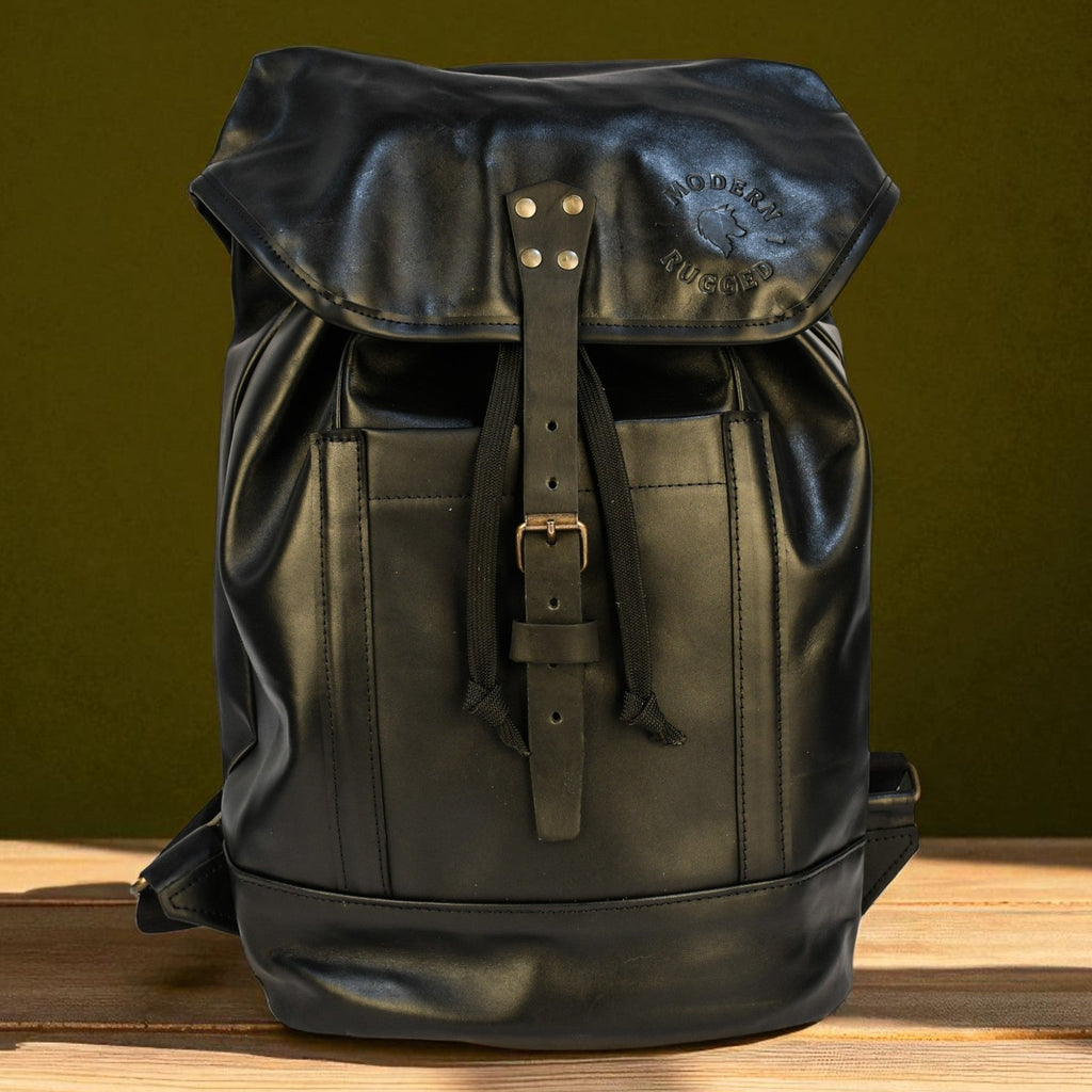 Black leather backpack on a wooden surface with a green background