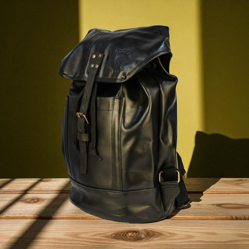 Black leather backpack on a wooden surface with a yellowish-green background