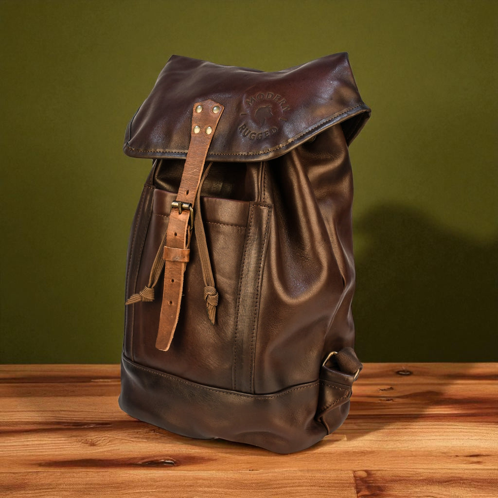 Brown leather backpack on a wooden surface with a green background