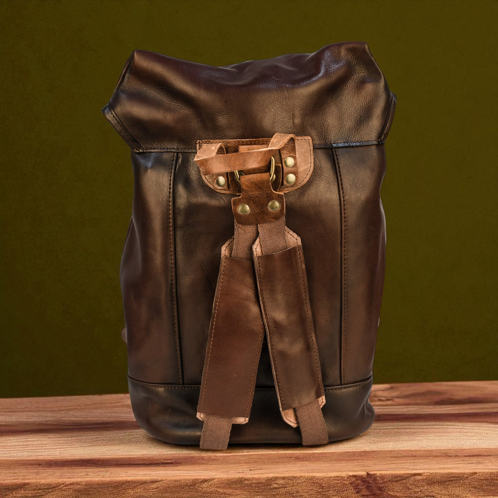 Brown leather backpack with straps on a wooden surface and green background