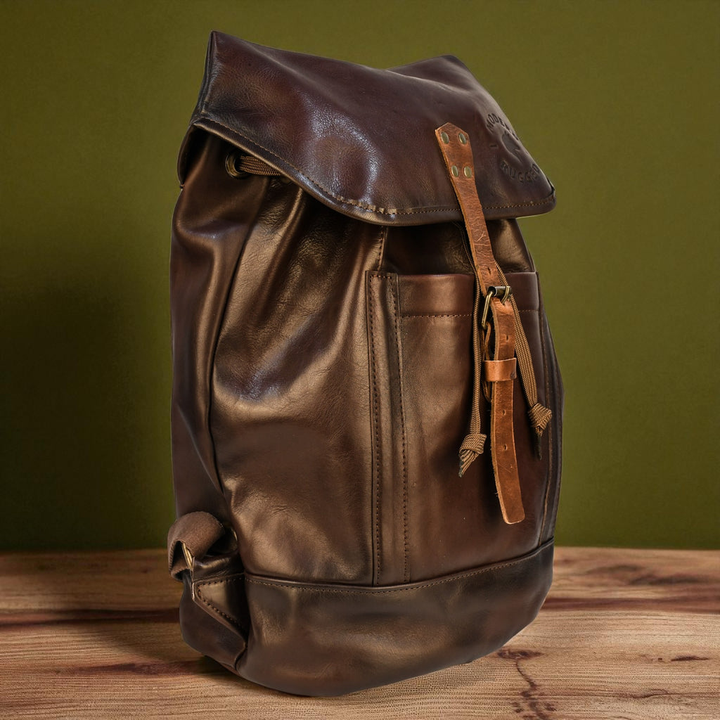 Brown leather backpack on a wooden surface with a green background