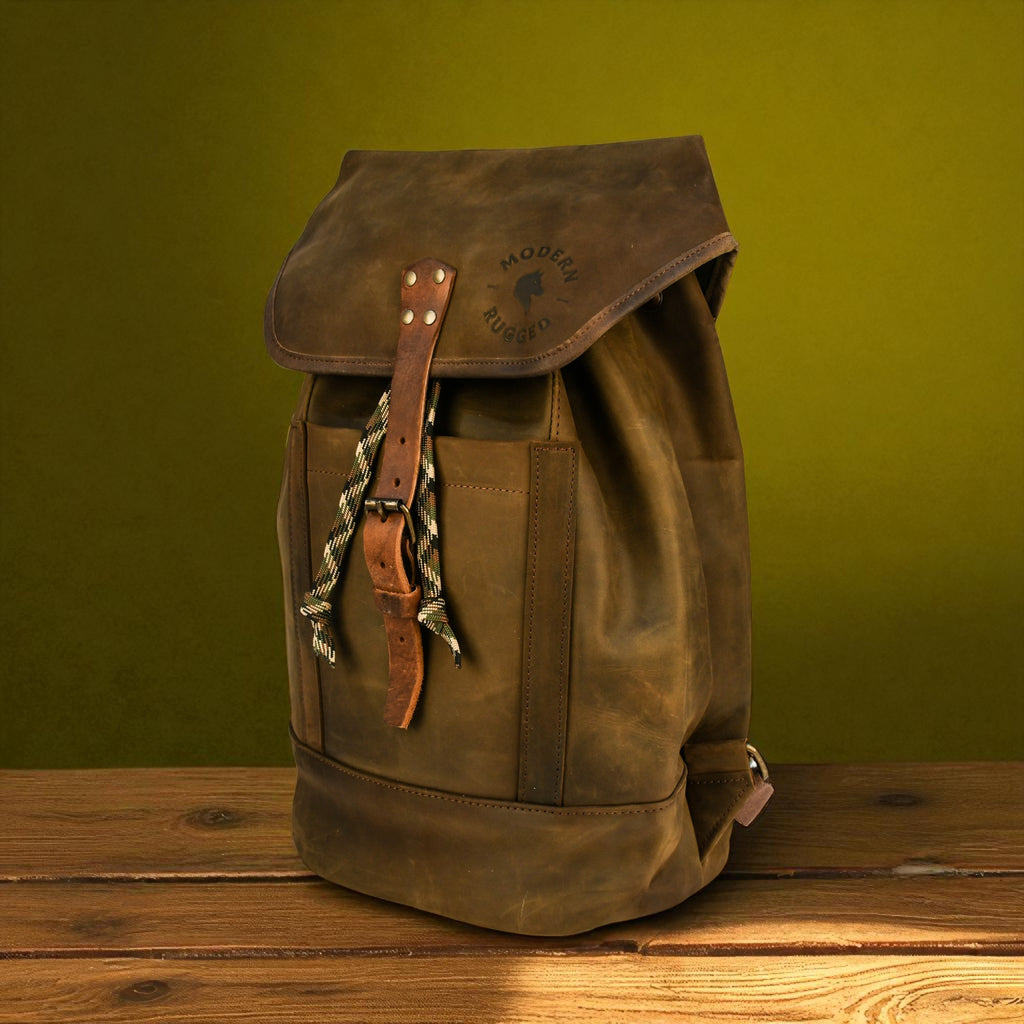 Olive leather backpack on a wooden surface with a green background