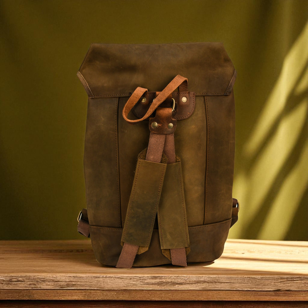 Olive leather backpack on a wooden surface with a green background