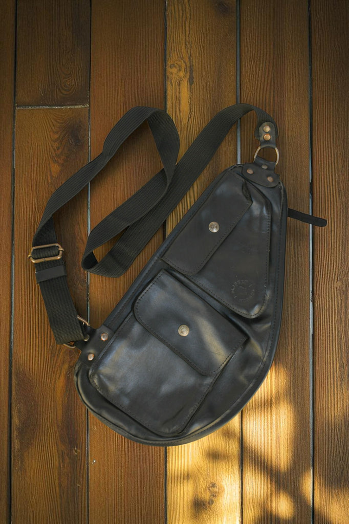 Black Bovine Leather Slim Sling - Black bag on a wooden surface