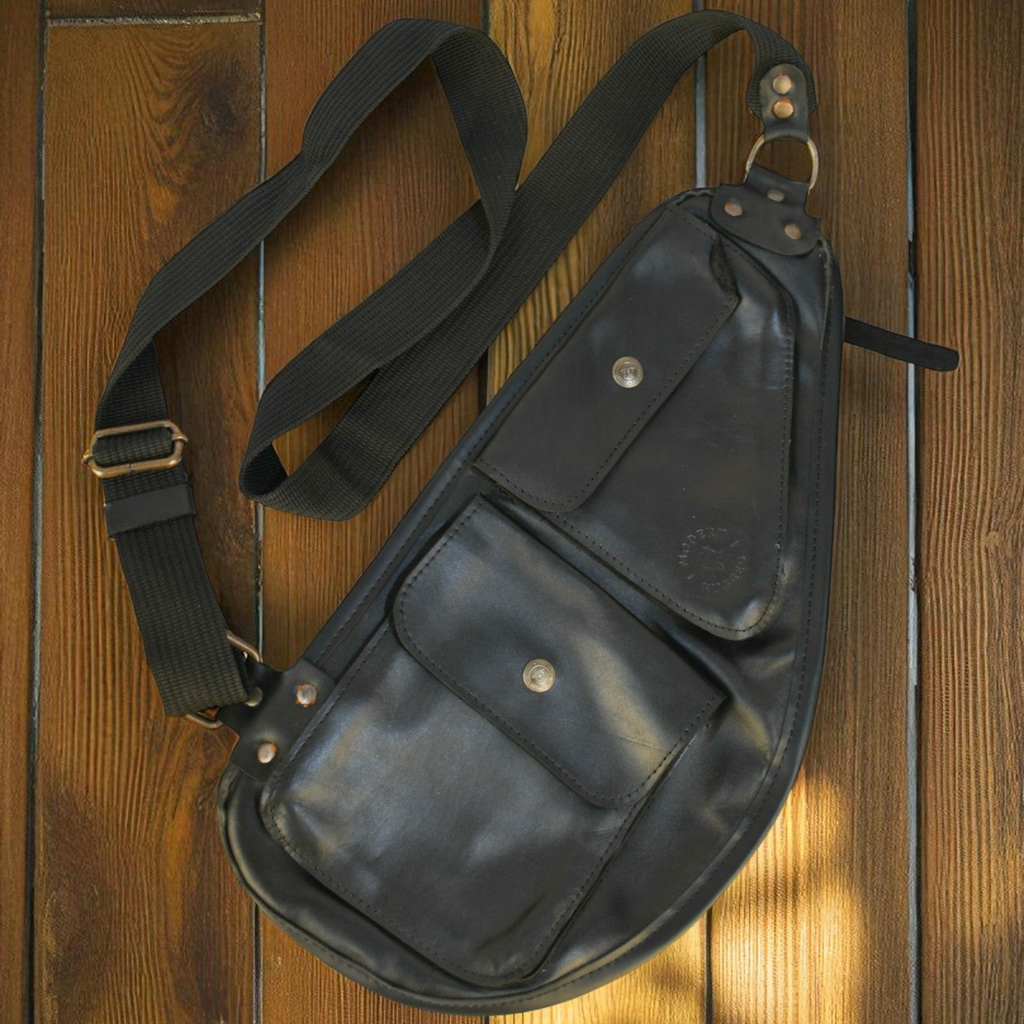 black leather slim sling bag on wooden table