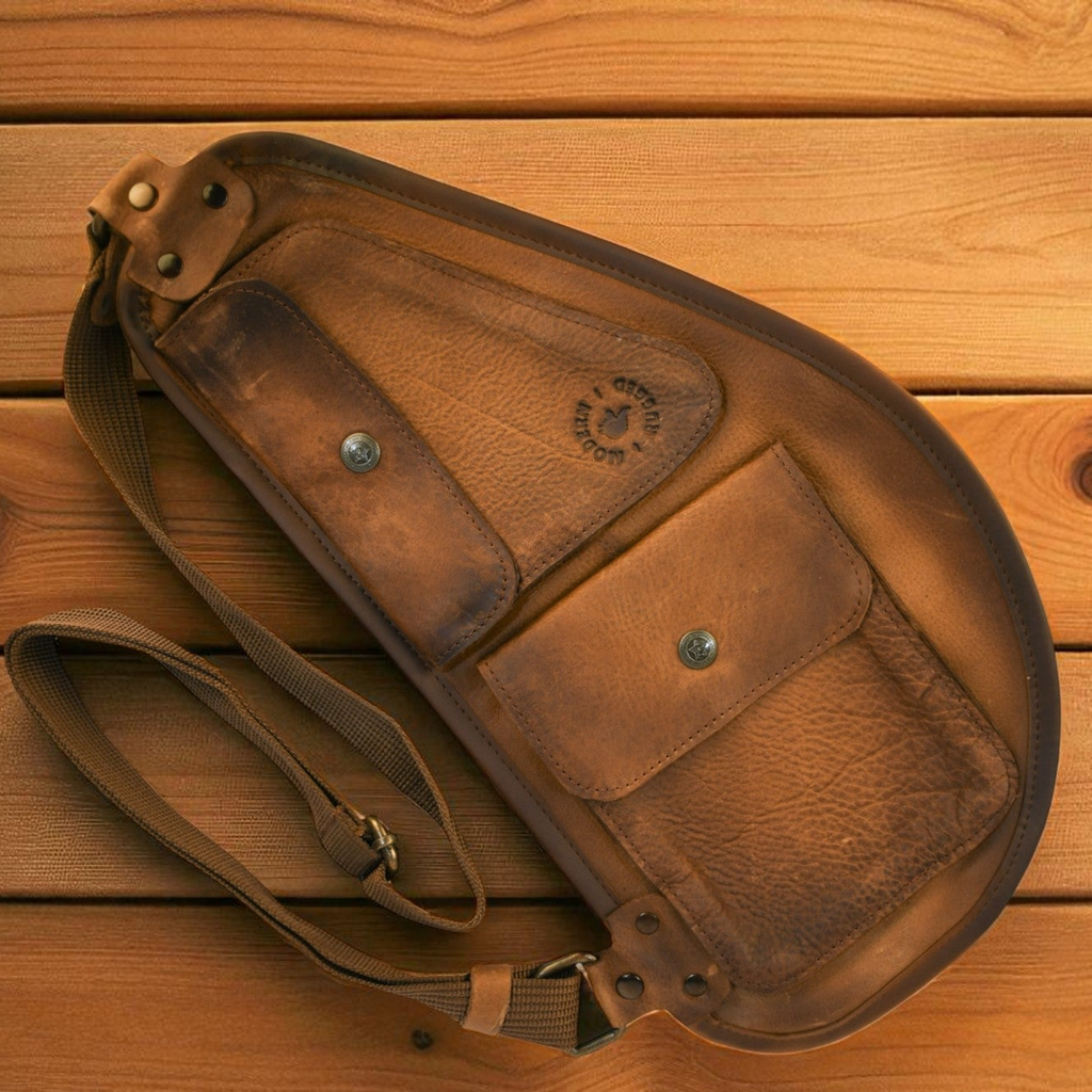 Brown leather pouch with strap on a wooden surface