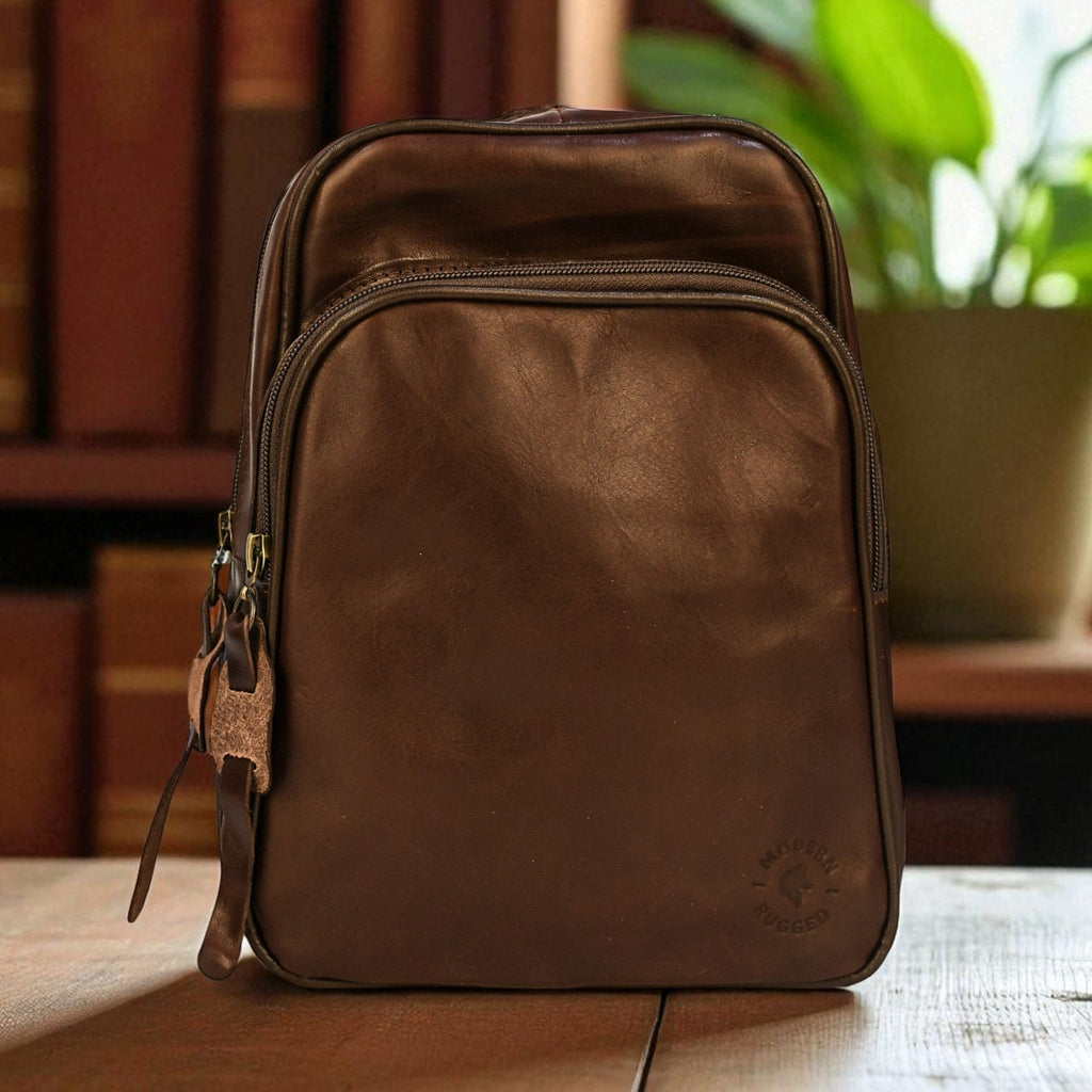 Brown leather bag on a wooden surface with books and a plant in the background