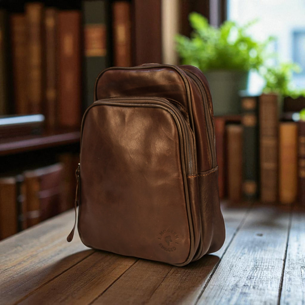 Brown leather backpack on a wooden table with books and plants in the background