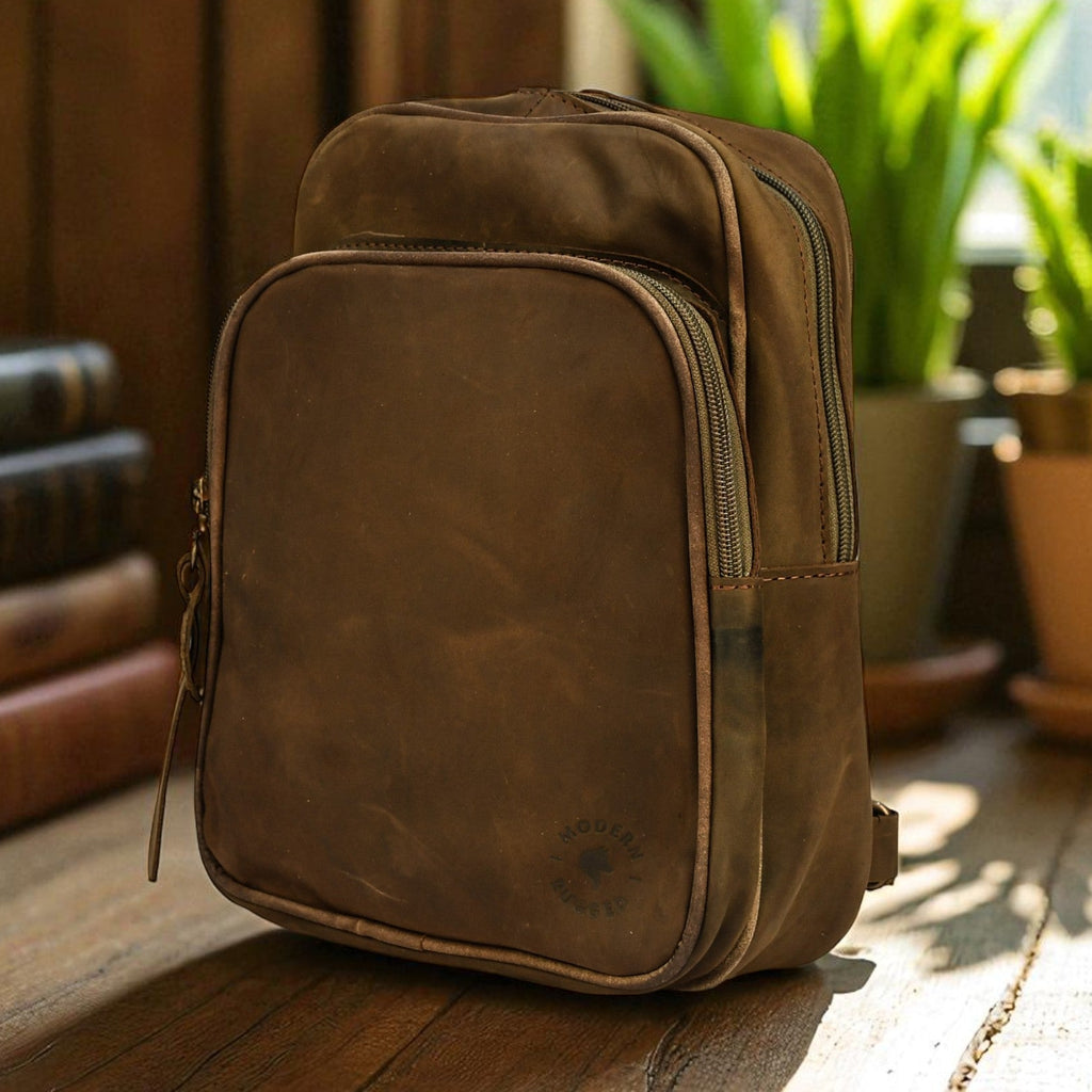 olive leather bag on a wooden surface with books and plants in the background
