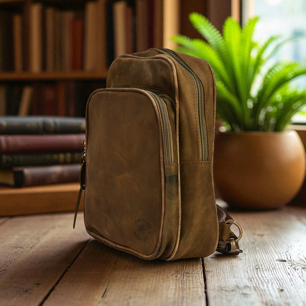 olive leather backpack on a wooden surface with books and a plant in the background