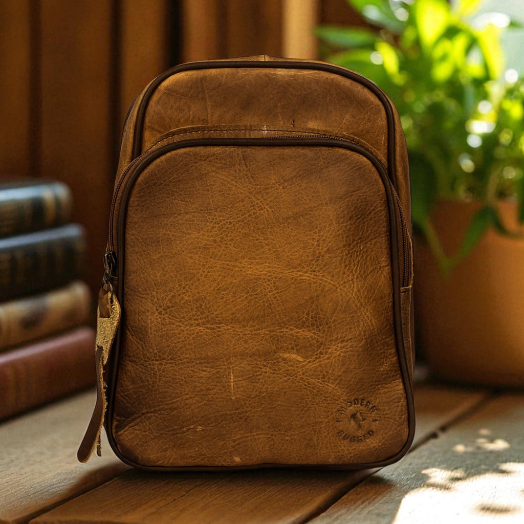Brown leather backpack on a wooden surface with books and a plant in the background