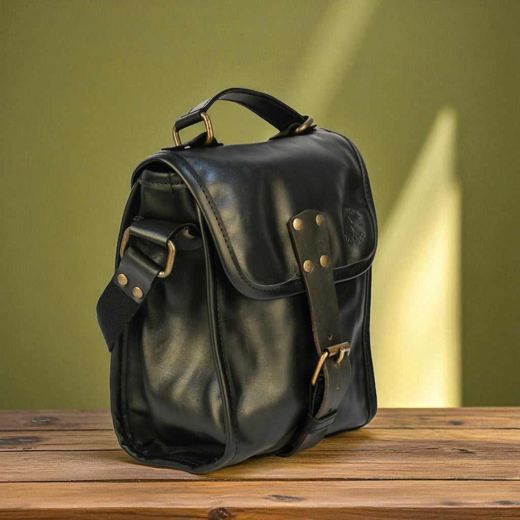 Black leather satchel bag on a wooden surface with a green background