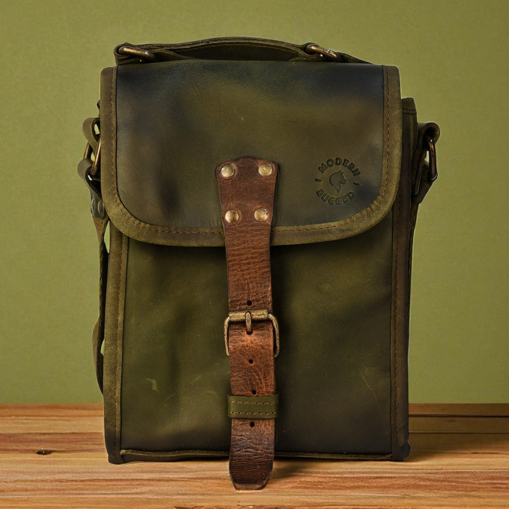 Green leather bag with brown strap on a wooden surface against a green background