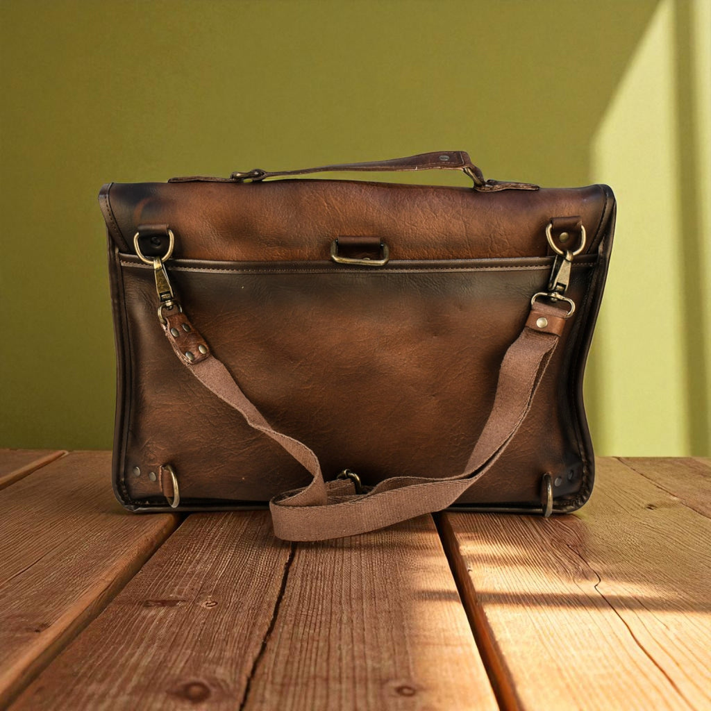 Brown leather laptop bag on a wooden surface with a green wall background