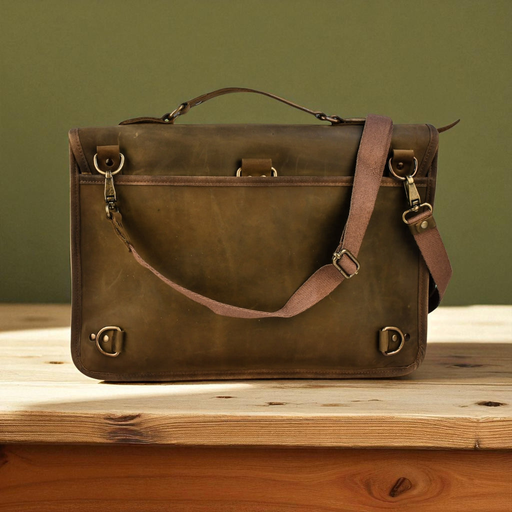 Brown leather satchel bag on a wooden surface with a green background
