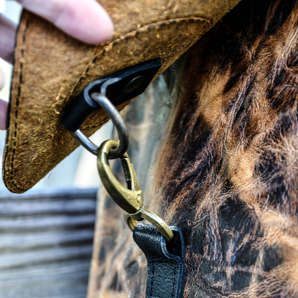Close-up of a leather strap with a brass clasp on a horse's bridle.