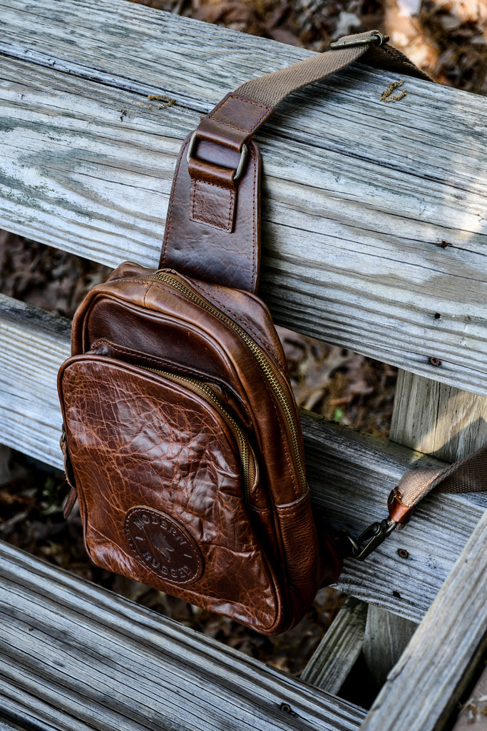 Brown leather waist bag on a wooden surface