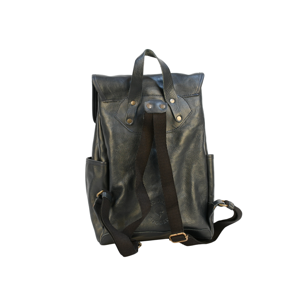 Dark leather modern rugged backpack on a wooden surface with books and a stone wall background